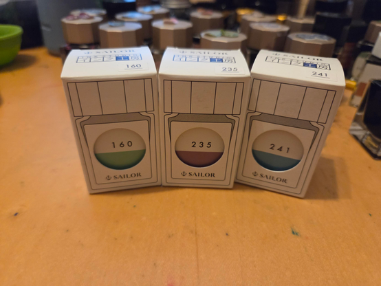 Three small bottles of ink in little boxes.