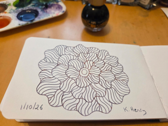 Hand drawn generative/procedural art in ink on an open page of my sketchbook. The abstract pattern is floral. My inks are next to my sketchbook.