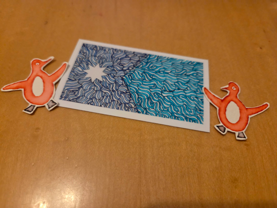 Sticker made from a hand drawing version of the minnesota flag with cut out hand drawn penguins on each side of it.