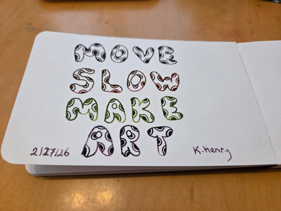 Hand drawn generative/procedural art in ink on an open page of my sketchbook. The abstract pattern is made of bubble letters with polka dots on them. The text reads "move slow make art"