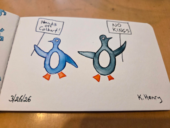 Hand drawn generative/procedural art in ink on an open page of my sketchbook. The abstract drawing looks a bit like two colorful penguins holding up protest signs that read "Hands off Colbert!" and "No Kings",