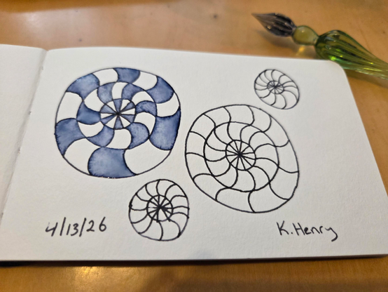 Hand drawn generative/procedural art in ink on an open page of my sketchbook. The abstract pattern looks a bit like candy or amenite fossils. My glass dipping pen is next to my sketchbook.