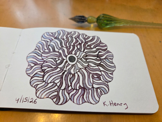 Hand drawn generative/procedural art in ink on an open page of my sketchbook. The abstract pattern is floral and my glass dipping pen is next to my sketchbook.