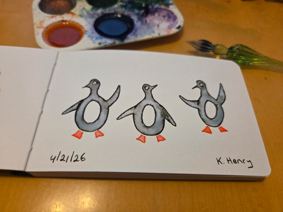 Hand drawn generative/procedural art in ink on an open page of my sketchbook. The abstract pattern looks like three penguins, with attitude. My glass dipping pen an inks are next to my sketchbook.
