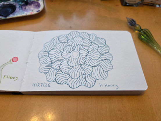 Hand drawn generative/procedural art in ink on an open page of my sketchbook. The abstract pattern is floral. My glass dipping pen is next to my sketchbook.