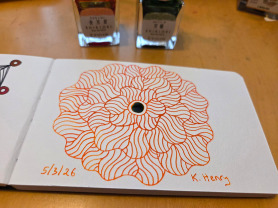 Hand drawn generative/procedural art in ink on an open page of my sketchbook. The abstract pattern is floral. There are ink bottles next to my sketchbook.