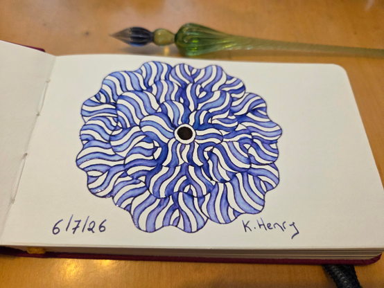 Hand drawn generative/procedural art in ink on an open page of my new sketchbook. The abstract pattern is floral. My glass dipping pen is next to my sketchbook.
