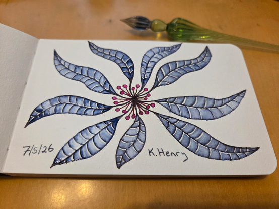 Hand drawn generative/procedural art in ink on an open page of my sketchbook. The abstract pattern looks a bit like a poinsettia, but with blue petals and differently shaped petals. My glass dipping pen is next to my sketchbook.