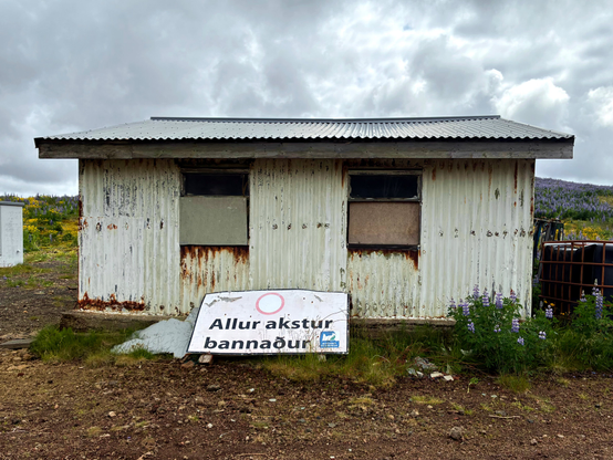 A shed with a sign leaning against it.