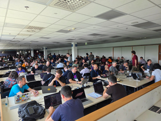 People discussions and working on laptops in the EuroPython sprint room. 