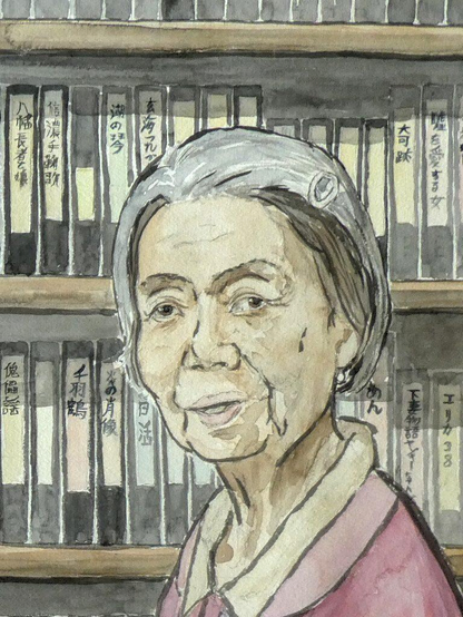 An elderly Japanese lady is looking benignly at the viewer, her head slightly tilted to one side. Her face is in three quarters profile. Her grey hair is cut to leave her neck free and fastened with a simple metal clip on the left of her head. Her clothes are nondescript, it looks like a cardigan of heavy cloth with a double collar of lighter material. Behind her are shelves, three rows high, with what looks like boxes for video tapes. Each is labelled with an inscription in Japanese.