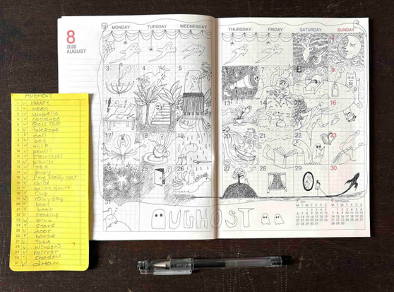 A photo of a planner open to August 2026, with each square filled with drawings of various ghosts. Next to it is a handwritten prompt list on a notepad, and a pen rests nearby. 