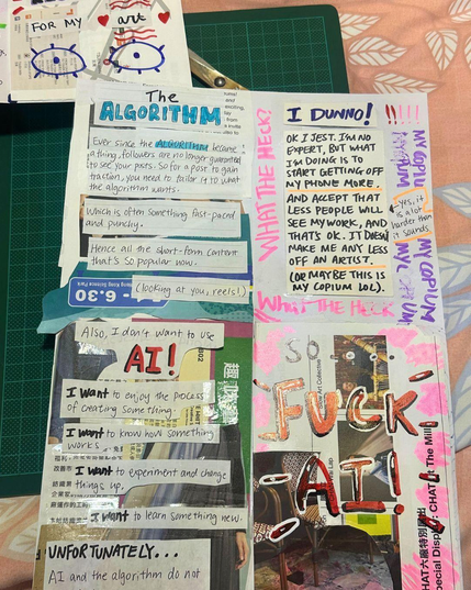 Slightly zoomed in photo of the behind the scenes of making the 'Social Media sucks for artists' zine. Page has a scissor behind it as well as a green cutting mat. This is placed on a pink blanket with white leaves.