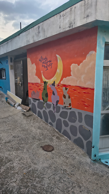Photo: 3 chats sont dessinés sur un mur, ils regardent un quartier de lune