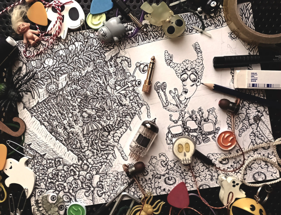 Photograph of an elaborate doodle of penned artwork, with random small objects and trinkets surrounding it.