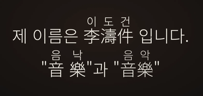 어두운 배경에 흰색 글씨로 "이도건, 제 이름은 李濤件 입니다. 음낙 '音樂'과 '音樂'"이라는 문구가 적혀 있습니다. 글자 위에는 작게 한글 독음이 병기되어 있습니다.